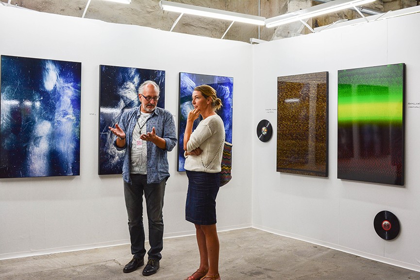 Visitors of the Discovery Art Fair discuss abstract paintings.