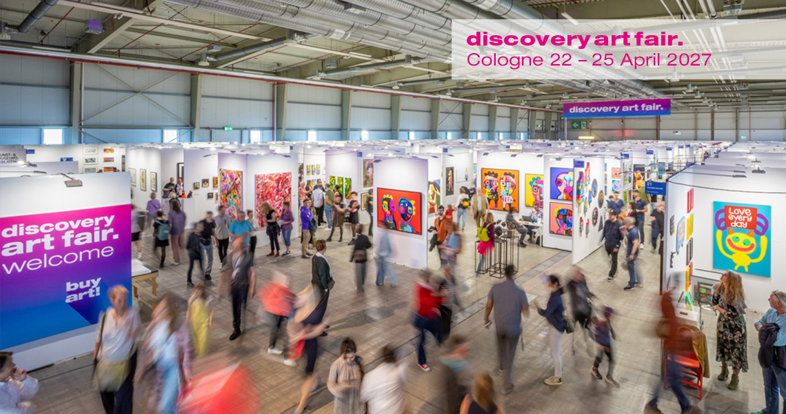 Visitors walk through the vibrant aisles of the Discovery Art Fair in Cologne, surrounded by colorful contemporary artworks displayed in gallery booths; the fair showcases emerging and established artists, creating a dynamic platform for buying and experiencing contemporary art.