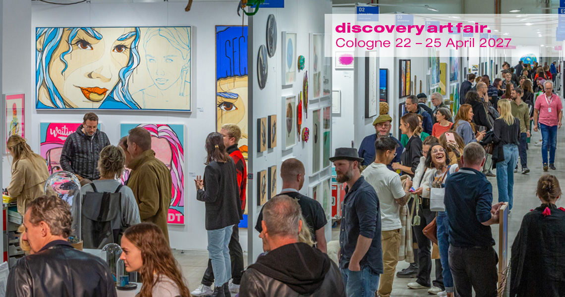 A picture of the Discovery Art Fair shows crowded aisles with numerous visitors visiting the various stands. A wide variety of artworks are on display at the stands, including paintings, sculptures and photographs.